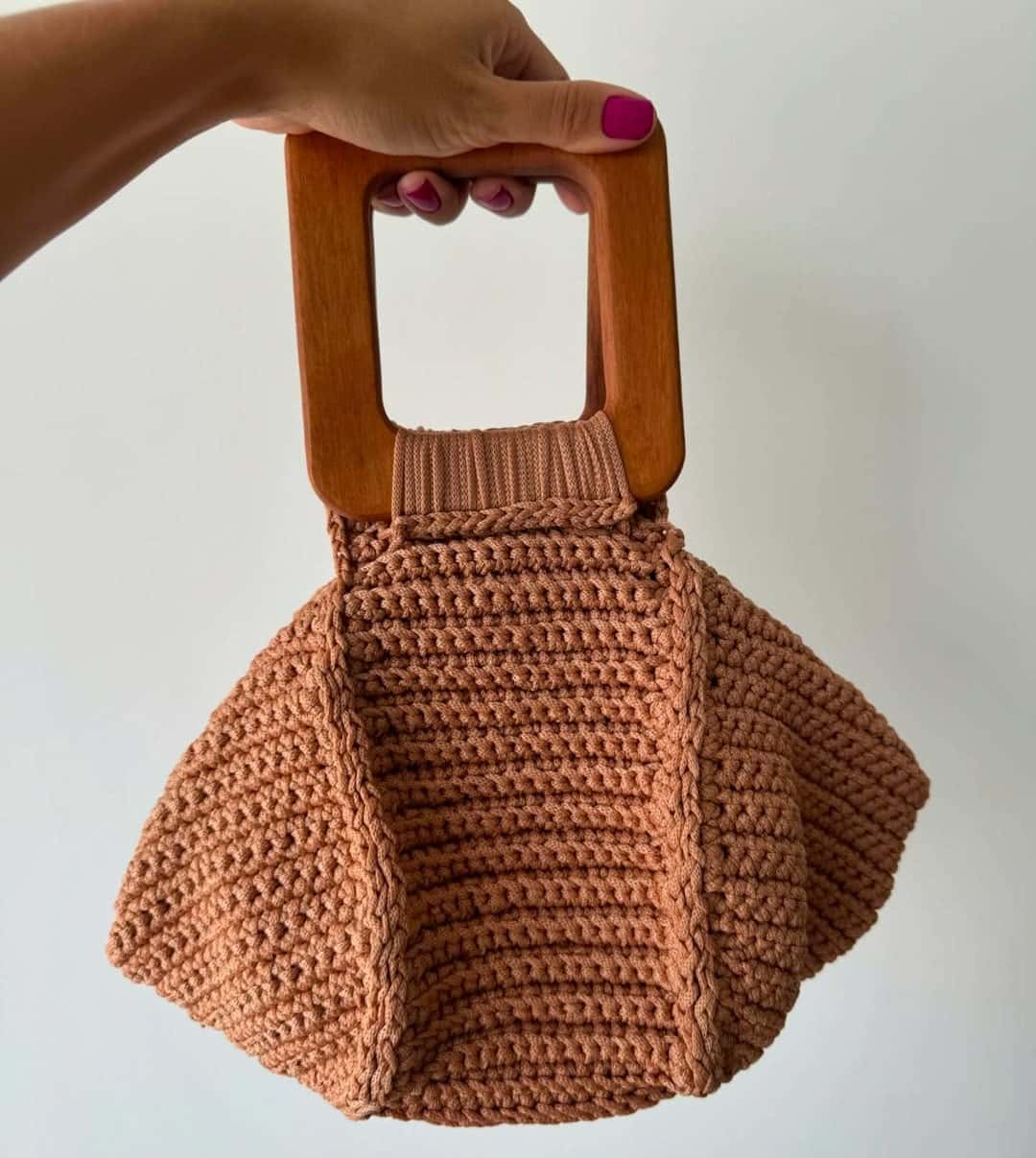 Bolsa Capri terracota com alça quadrada de madeira, segurada pela mão