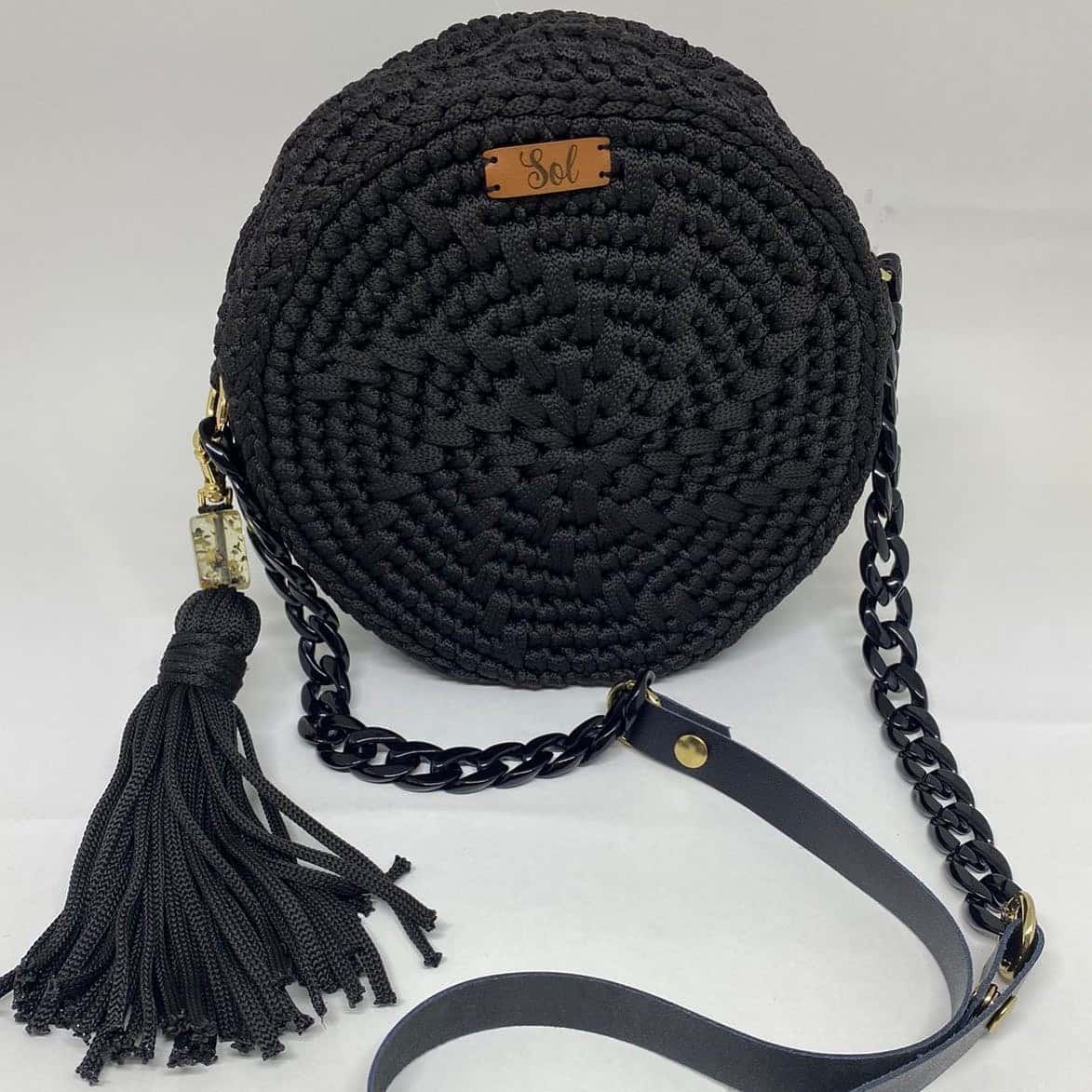 Bolsa Jacarta redonda preta com corrente preta, alça tipo couro e tassel