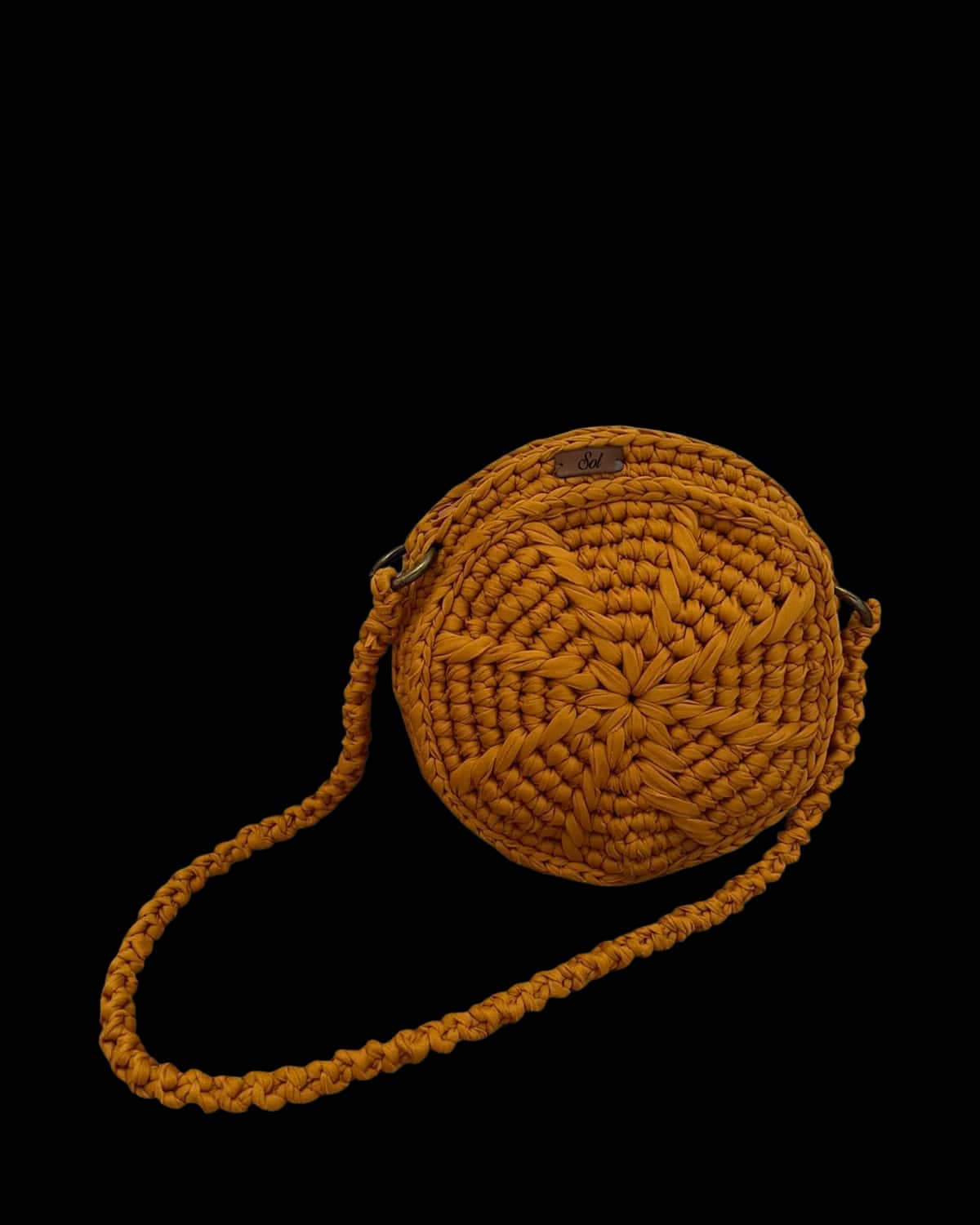 Bolsa Jacarta redonda caramelo com estrela em relevo e alça trançada, foto de catálogo em fundo neutro
