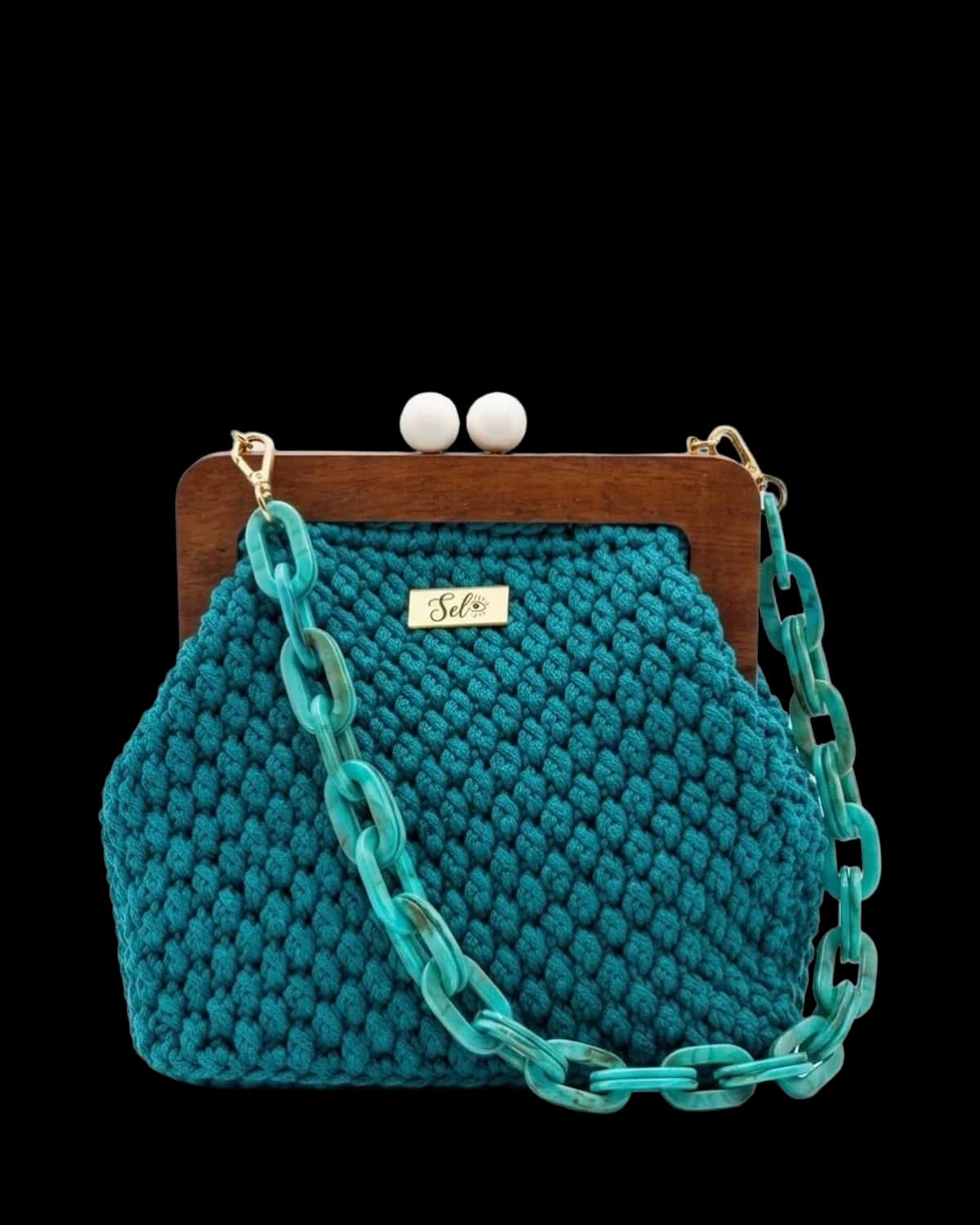 Bolsa Mykonos em crochê azul-petróleo com fecho de madeira e alça de corrente turquesa, foto de catálogo em fundo neutro
