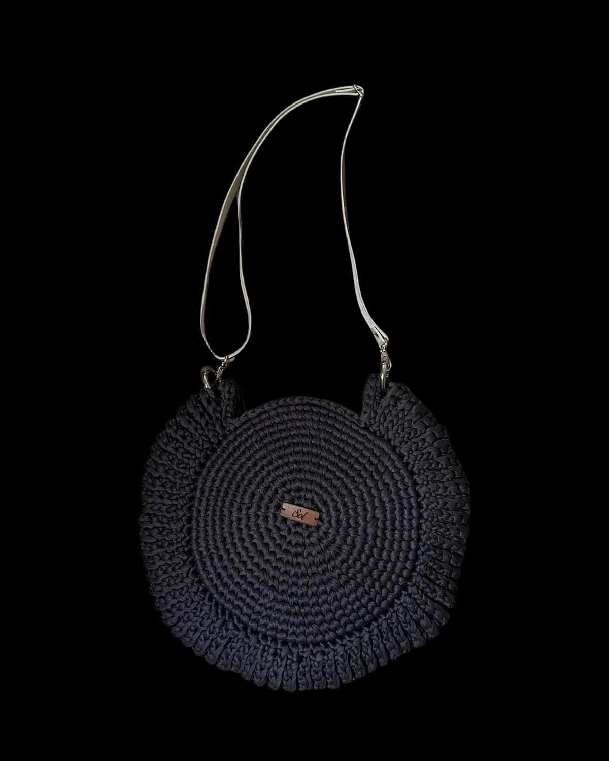 Bolsa Paraty redonda preta com babado em crochê e alça tipo couro clara, foto de catálogo em fundo neutro