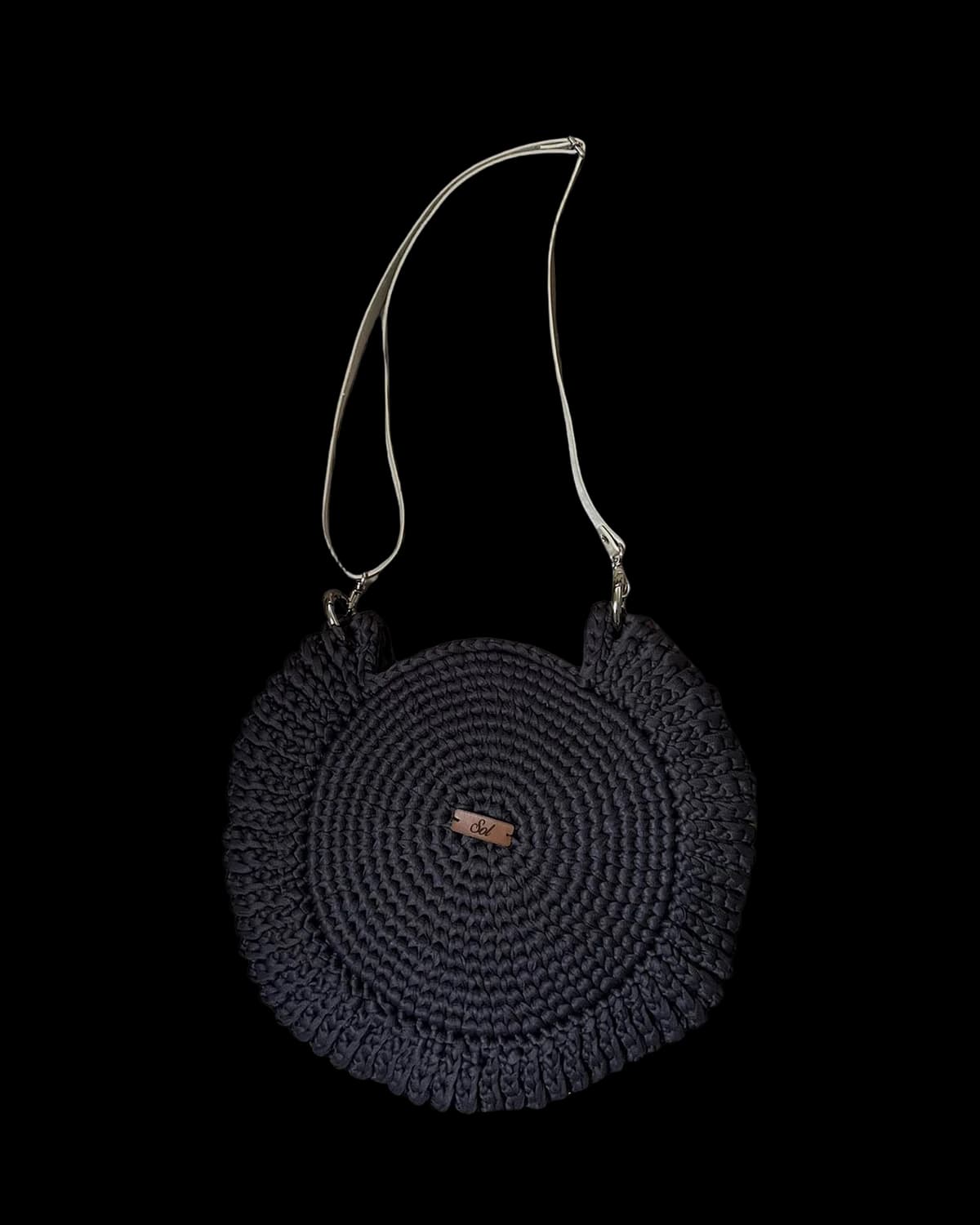 Bolsa Paraty redonda preta com babado em crochê e alça tipo couro clara, foto de catálogo em fundo neutro