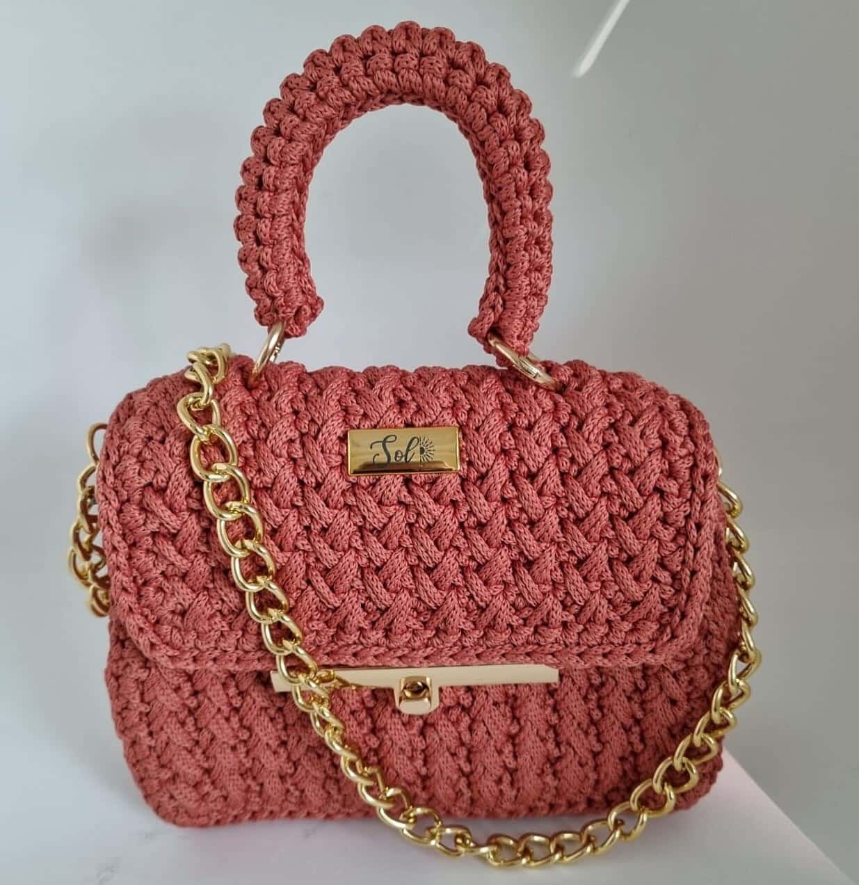 Bolsa Singapura coral com alça de mão em crochê, fecho dourado e corrente dourada de elos grandes