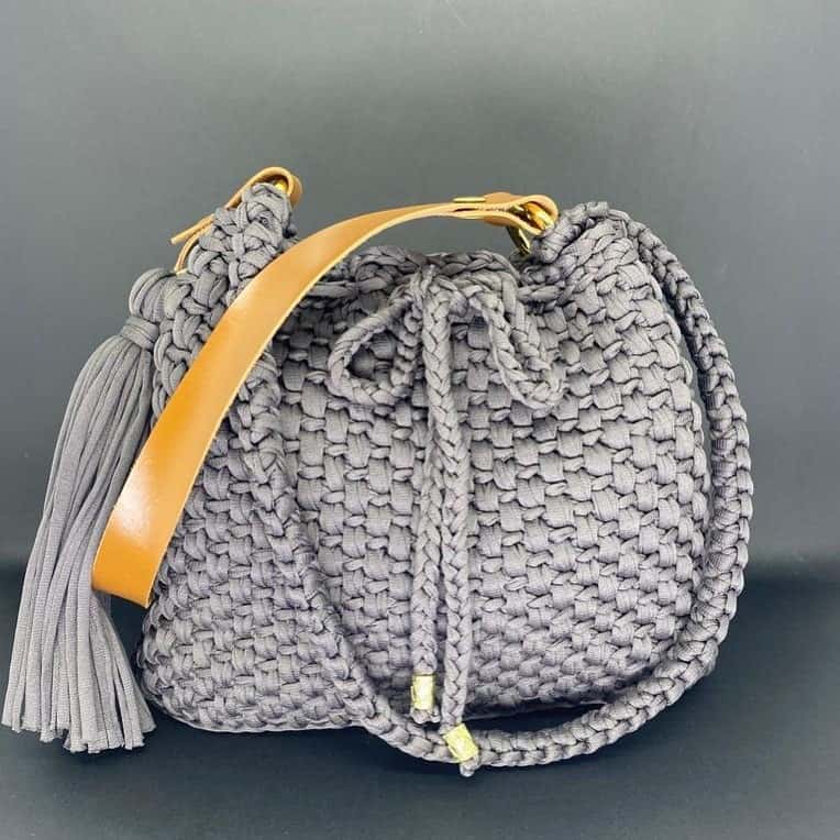 Bolsa saco Viena cinza com tassel e alça tipo couro caramelo