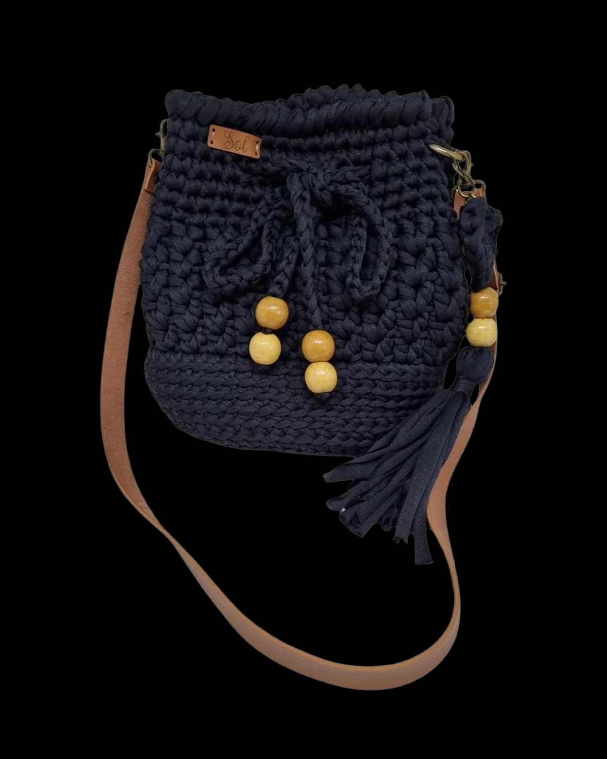 Bolsa saco Viena azul-marinho com contas de madeira, tassel e alça tipo couro caramelo, foto de catálogo em fundo neutro