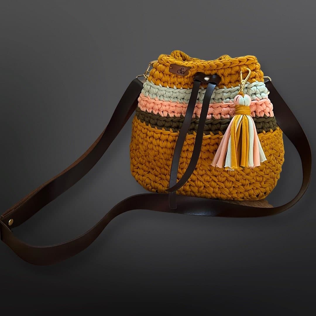 Bolsa saco Viena Mini mostarda com listras coloridas, tassel e alça tipo couro marrom